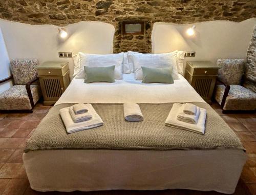a bedroom with a large bed with towels on it at A Maquía de Medín in O Pino 