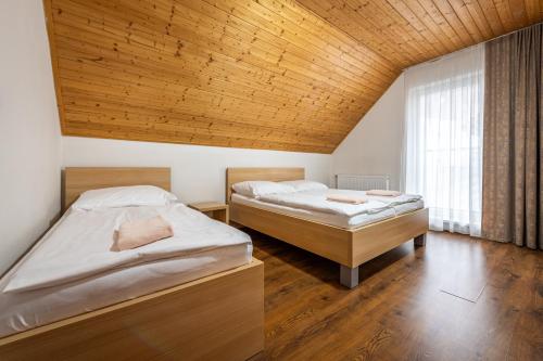 two beds in a room with a wooden ceiling at Chata Majocka Martin Strane, Ferrata in Martin