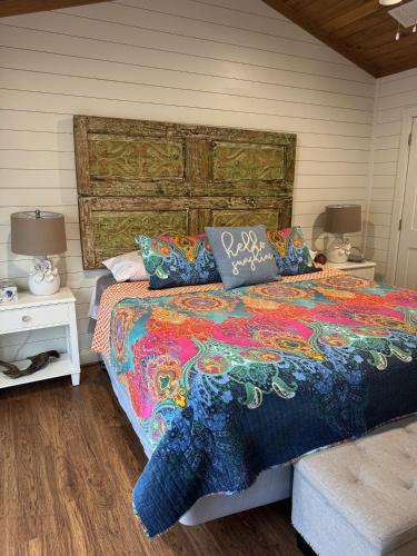 a bedroom with a bed with a colorful blanket and pillows at Hot Tub Firepit Dreams Streamside Hochatown in Broken Bow