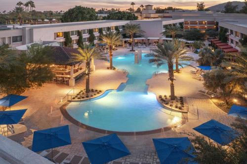 an overhead view of a pool with palm trees and blue umbrellas at The Scottsdale Resort & Spa, Curio Collection by Hilton in Scottsdale