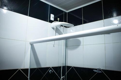 a shower in a bathroom with black and white tiles at Pousada da Isa in Quatro Barras