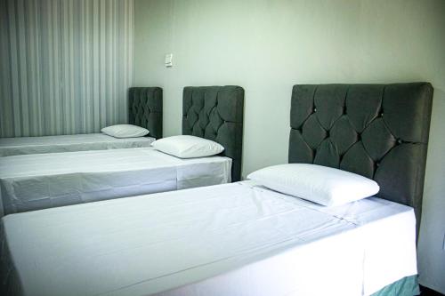 two beds in a room with white sheets at Pousada da Isa in Quatro Barras