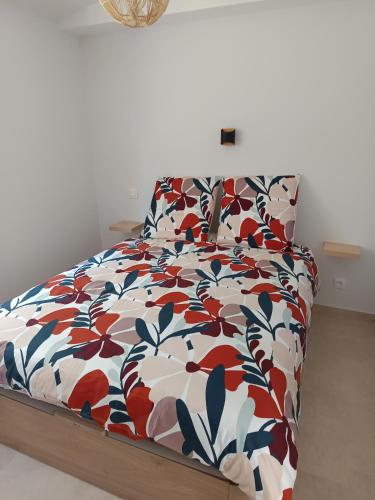 a bed with a flowered comforter in a bedroom at Appartement Marilou in Pompiey