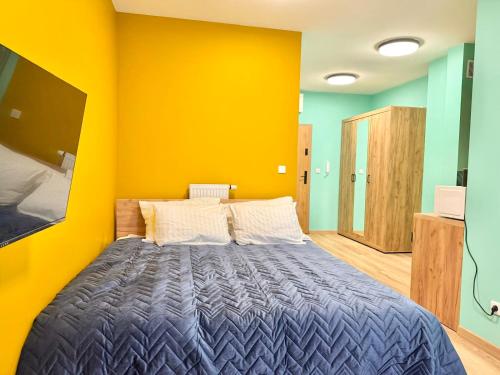 a bedroom with a bed with a yellow wall at Rumia Apartment by JumpInHere in Rumia