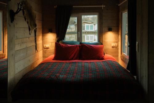 ein Schlafzimmer mit einem Bett mit roten Kissen und einem Fenster in der Unterkunft Chalet WILD in Geel