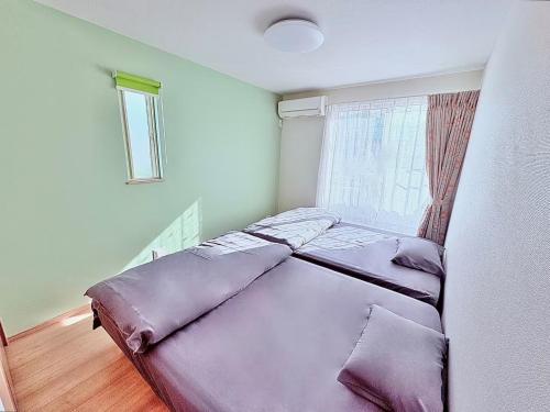 a bed with purple pillows in a room with a window at SAKURA HOTEL - Vacation STAY 35483v in Hanawadamachi