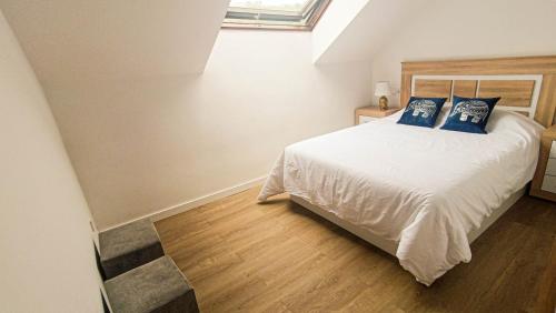 a bedroom with a bed with blue pillows on it at Atico moderno en Langreo in Langreo