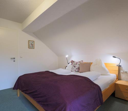 a bedroom with a large bed with purple sheets and pillows at Bachbauer am Attersee in Weyregg