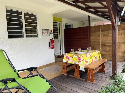 a patio with a table and chairs on a deck at Les 2 Cocotiers - Studios in Sainte-Luce