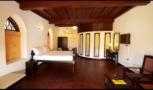 a bedroom with a bed in a room with wooden floors at The Heritage Kochi in Cochin