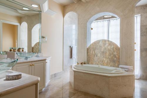 y baño grande con bañera y ducha. en Olde Marco Island Inn and Suites, en Marco Island