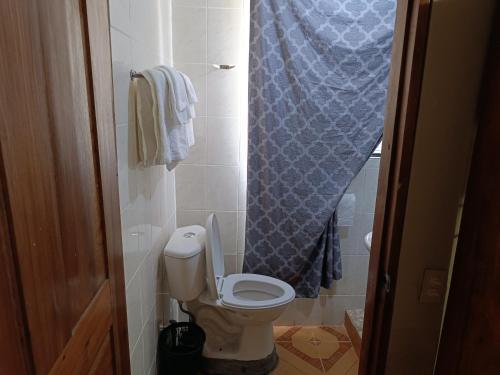 a bathroom with a toilet with a blue shower curtain at Sweet Dreams in Bluefields