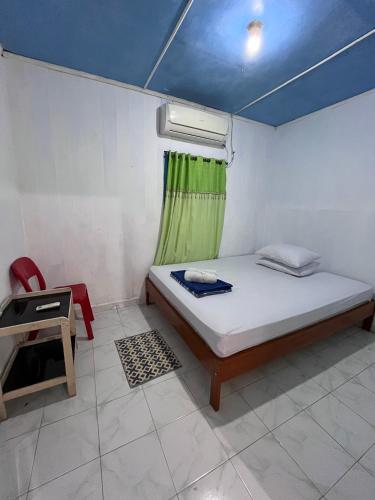 a small bedroom with a bed and a window at Ipoeng Rest Bed & Breakfast in Gorontalo