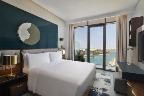 a bedroom with a large white bed and a large window at Conrad Bahrain Financial Harbour in Manama