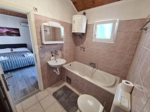 a bathroom with a sink and a tub and a toilet at House Beachfront Delight in Neviđane