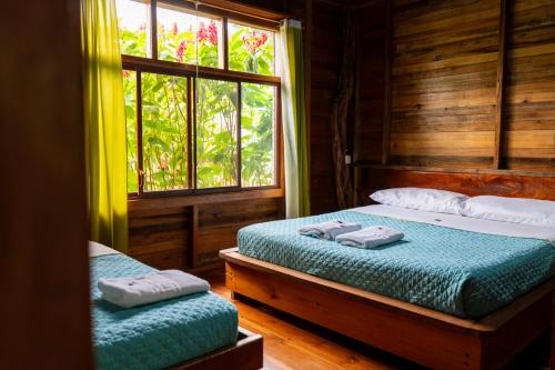 a bedroom with two beds and a window at Coati Lodge Misahualli in Tena