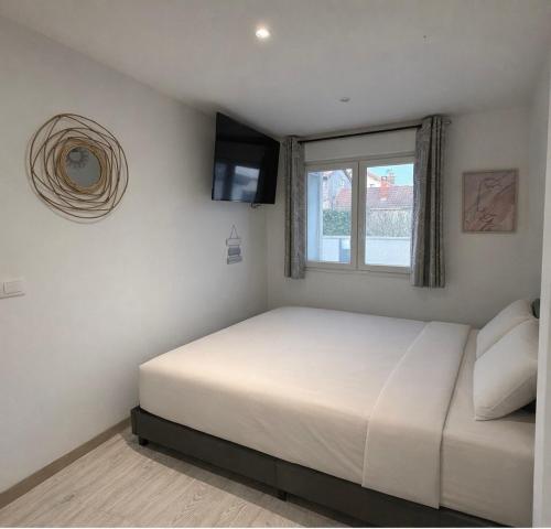 a white bedroom with a bed and a window at Maison avec piscine in Golbey