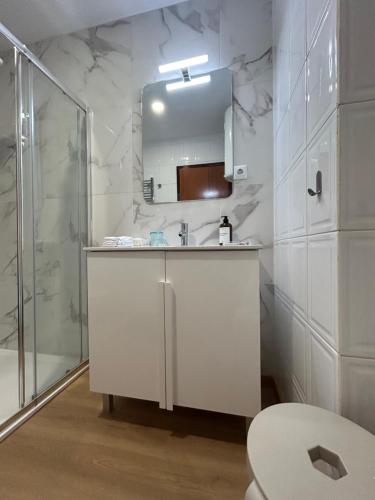 a white bathroom with a sink and a shower at Boavista Apartments in Paredes de Coura