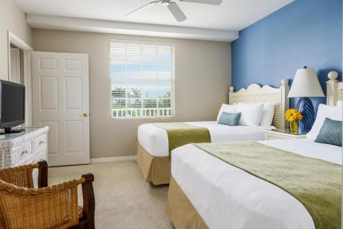 a hotel room with two beds and a television at Olde Marco Island Inn and Suites in Marco Island