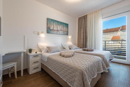 a white bedroom with two beds and a window at Villa Ursula in Pakoštane