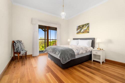 a white bedroom with a bed and a chair at Tiverton in Kurrajong