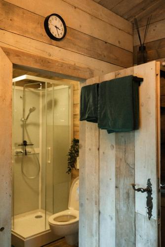 ein Badezimmer mit Dusche und einer Uhr an der Wand in der Unterkunft Chalet WILD in Geel