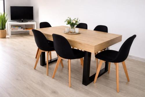 a dining room table with black chairs and a television at Market Apartment - VPA in Vila Praia de Âncora