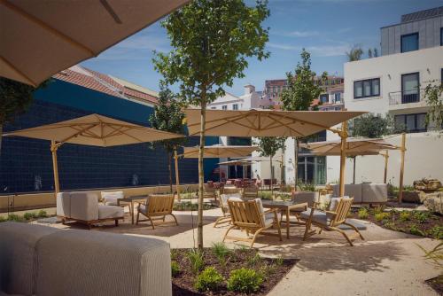 a patio with tables and chairs and umbrellas at DUO Hotel Lisbon, Curio Collection by Hilton in Lisbon