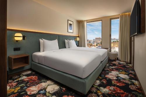 a large white bed in a room with a window at DUO Hotel Lisbon, Curio Collection by Hilton in Lisbon
