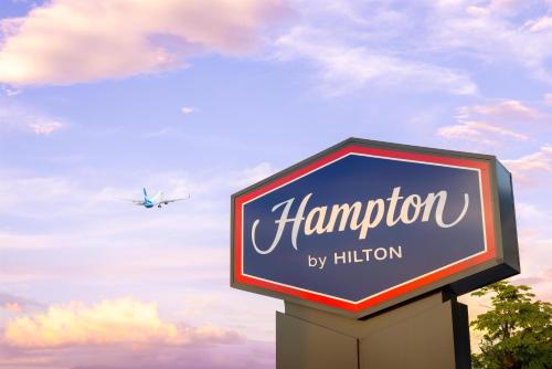a sign for a hampton motel with an airplane at Hampton By Hilton Guanacaste Airport in Liberia