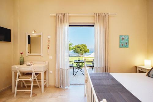 a bedroom with a bed and a desk and a window at Thalassa Apartments & Studios in Kavos