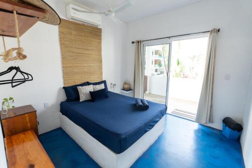 a bedroom with a blue bed and a large window at Suku'un in Brisas de Zicatela