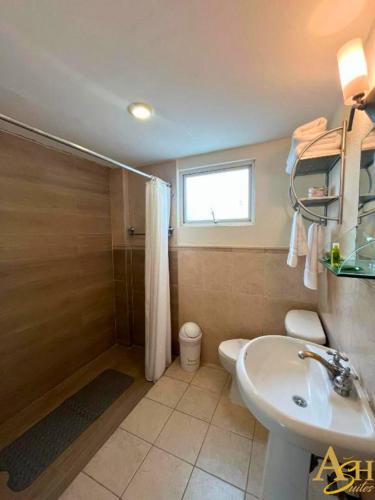 a bathroom with a sink and a toilet and a window at Angeles Suites & Hotel in Veracruz