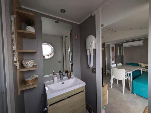 a bathroom with a sink and a dining room at Bungalow mahi-mahi in Lacanau