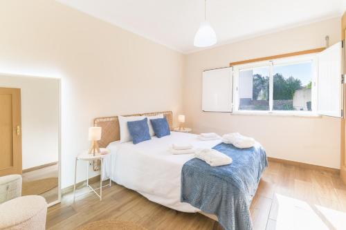 a white bedroom with a large bed with blue pillows at Blue Horizon Apartment - Costa Alentejana in Santiago do Cacém