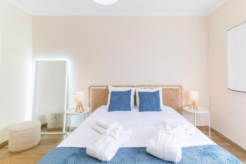 a bedroom with a large white bed with blue pillows at Blue Horizon Apartment - Costa Alentejana in Santiago do Cacém