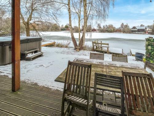 a table and chairs on a deck with a snow covered lake at Avocet Lodge in Horncastle