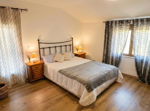 ein Schlafzimmer mit einem großen Bett und zwei Fenstern in der Unterkunft Casa El Pedernal in Basardilla