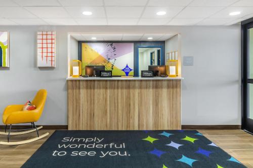 a lobby with a reception desk and a yellow chair at Spark By Hilton Roanoke Airport in Roanoke