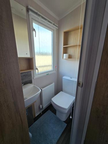 a small bathroom with a toilet and a sink at Pine Ridge B6 in Reighton