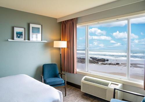 a room with a bed and a window with a view of the beach at The Coho Oceanfront Lodge in Lincoln City