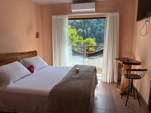 a bedroom with a bed and a large window at Pousada & Hospedagem Estação in Domingos Martins