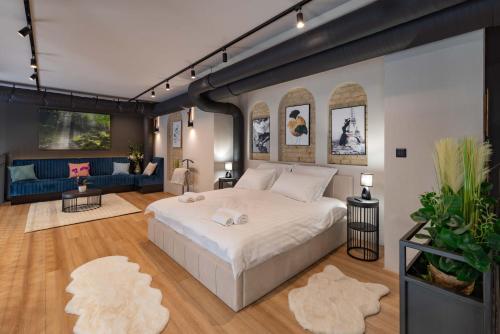a bedroom with a large white bed and a blue couch at R2 apartman in Kecskemét