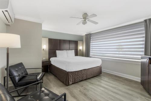 a bedroom with a bed and a chair and a window at Best Western Historic Bayfront in St. Augustine