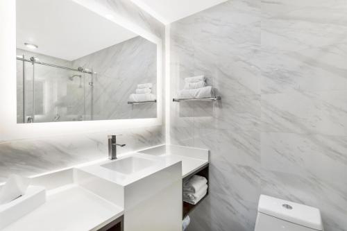 a white bathroom with a sink and a mirror at Best Western Historic Bayfront in St. Augustine