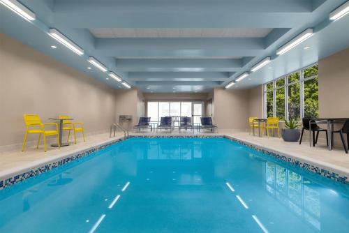 a swimming pool with yellow chairs and tables and chairs at Home2 Suites By Hilton Virginia Beach Princess Anne in Virginia Beach