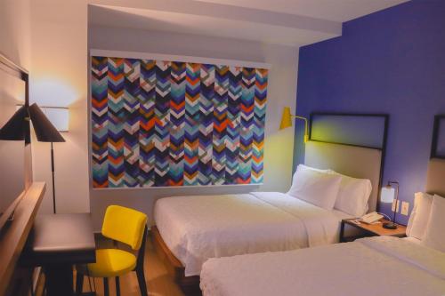 a hotel room with two beds and a painting on the wall at Tru By Hilton Puebla Angelopolis in Puebla