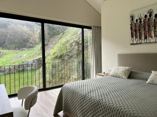 a bedroom with a bed and a large window at Ermida Vista Douro in Baião