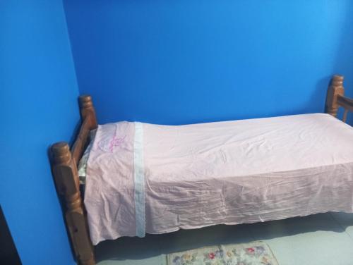 a small bed in a room with a blue wall at Casa inteira in Ponta Grossa