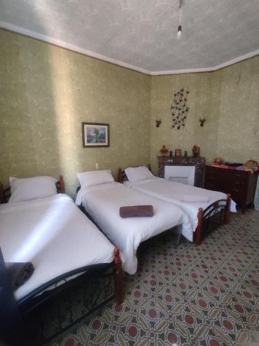 a bedroom with three beds with white sheets at Appartement 3 pièces in LʼAgha